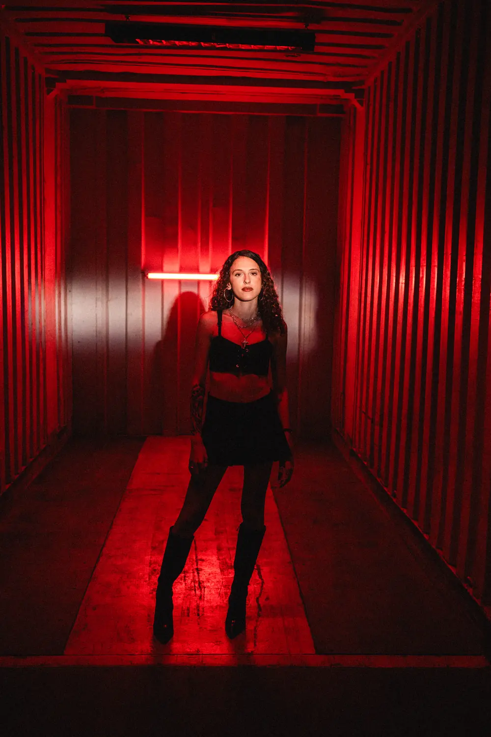 Vairy RS de cuerpo entero en un pasillo iluminado con luz roja